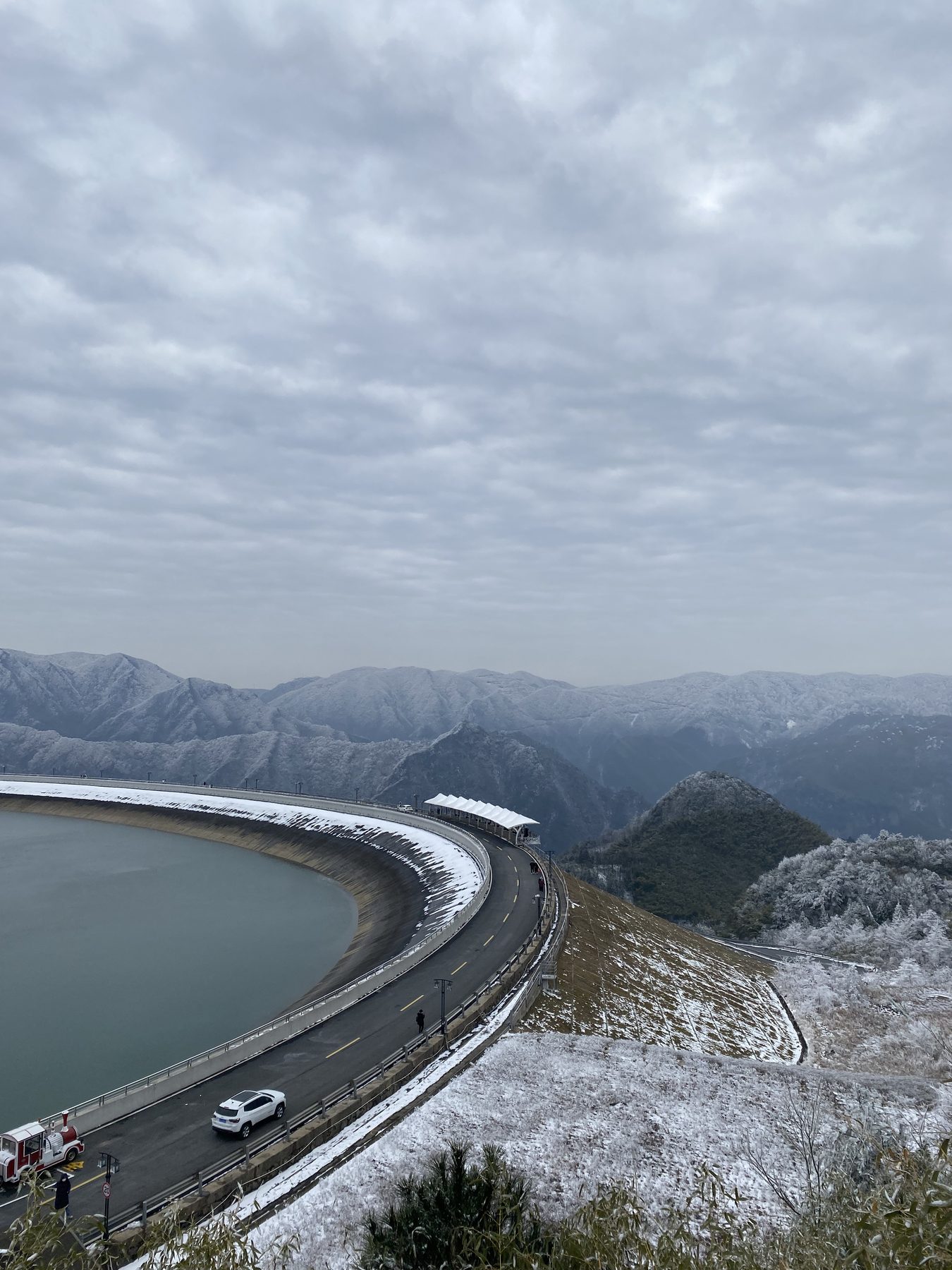 A reservoir road curving through snow-covered mountains in Anji, Zhejiang