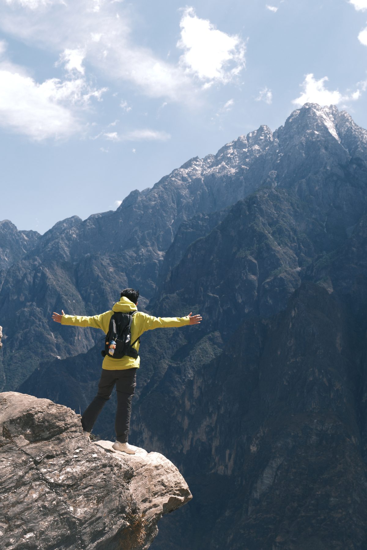 Aspen opening his arms on a cliff at Tiger Leaping Gorge in Yunnan