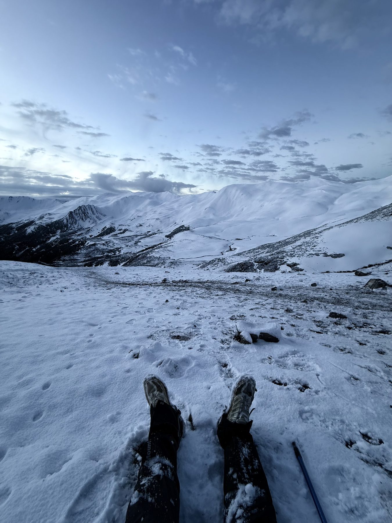 Boots resting in snow in front of mountains in Western Sichuan